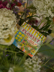 Florist house matchbox beside a bouquet of flowers