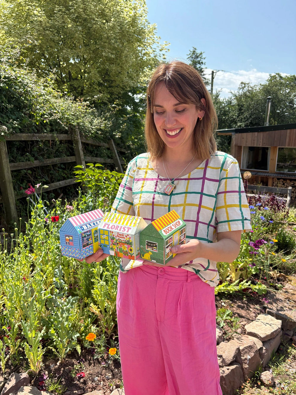 A girl holding the house matchbox in front of a garden