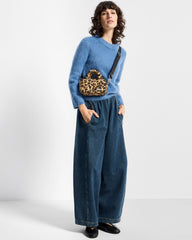 Model wearing the Feline mini bag across the body with a blue sweater and wide jeans